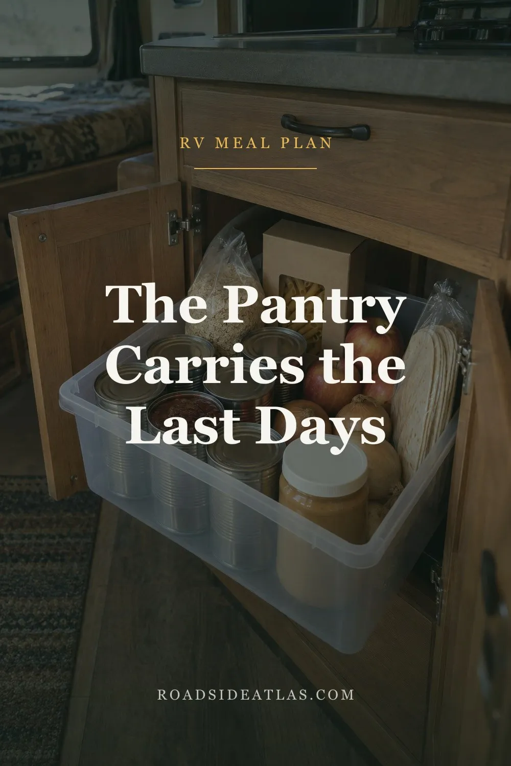 A clear bin in a lower RV cabinet holding canned beans, oats, pasta, peanut butter, apples, onions and tortillas