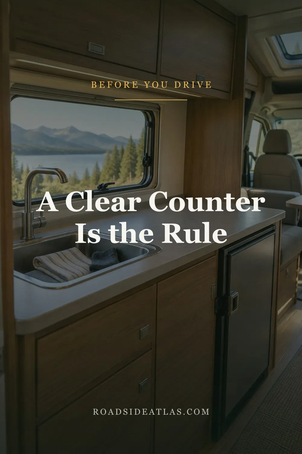 A motorhome galley ready to drive: a clear counter, towels in the sink, the fridge door latched