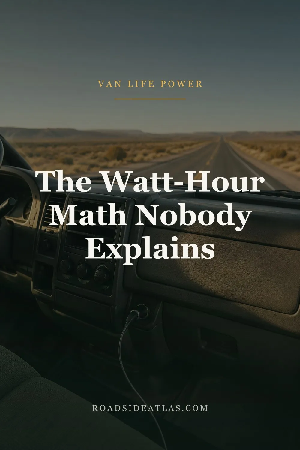 The dashboard of a campervan on an empty two-lane desert highway at sunset, with a charging cable plugged into the socket below the vents